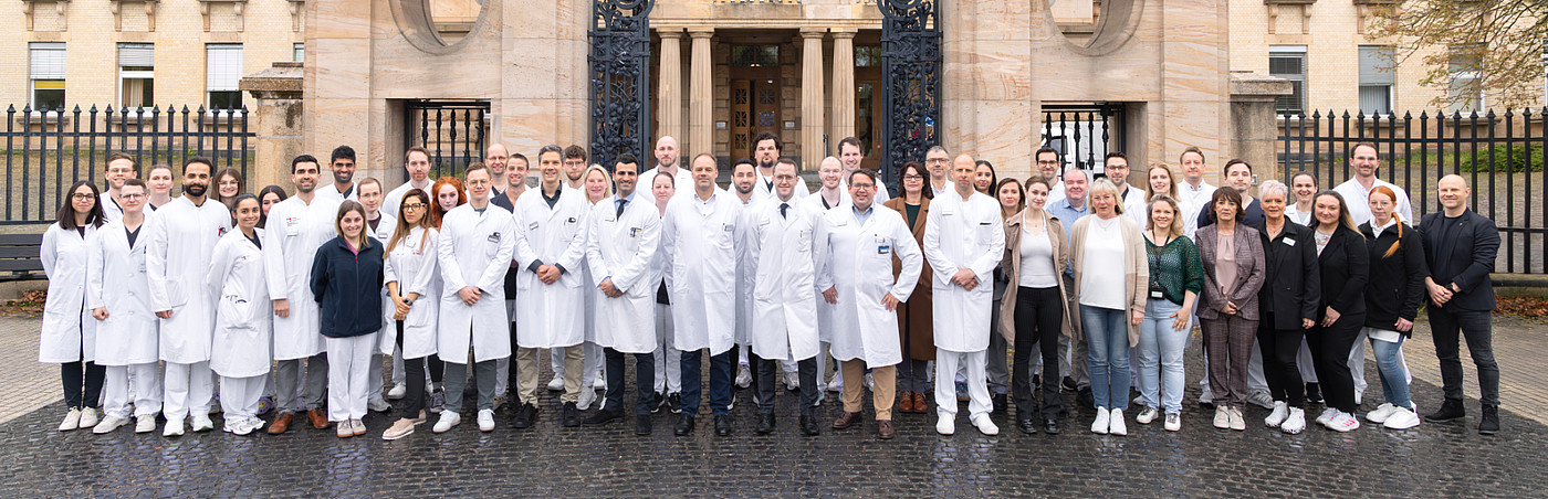 Gruppenfoto von den Mitarbeiterinnen und Mitarbeitern des Orthopädisch-Unfallchirurgischen Zentrums vor dem historischen Haupteingang des Universitätsklinikums Mannheim