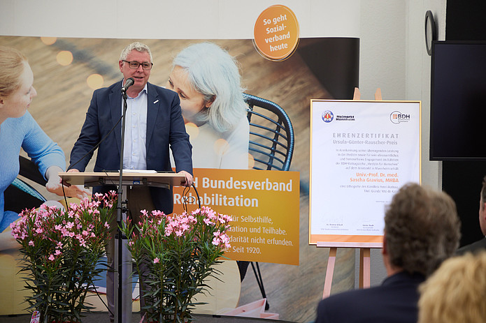 Mann im schwarzen Anzug hält Rede bei Preisverleihung