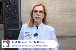 Professor Nicole Rotter im weißen Kittel vor historischer Eingangstor
