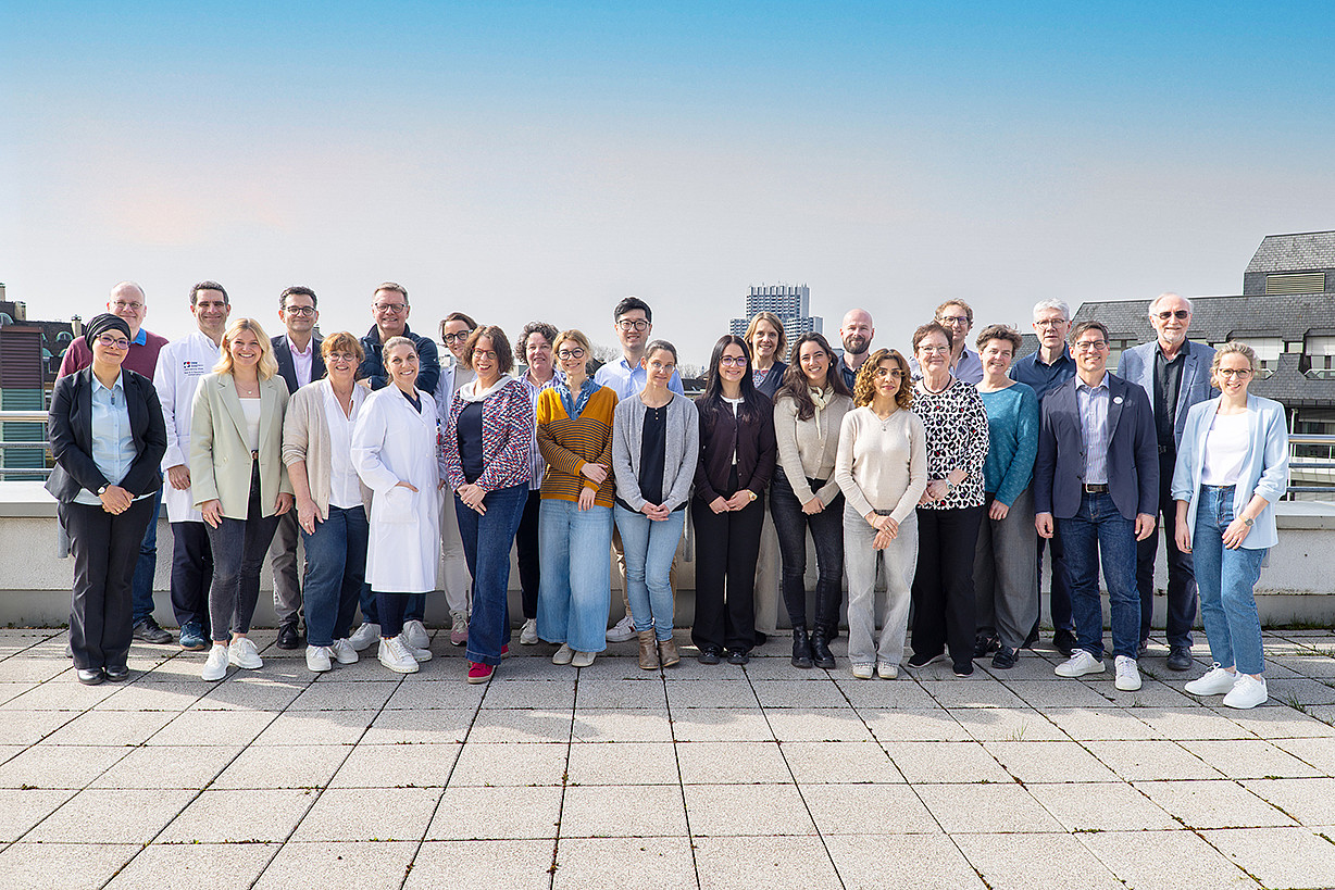 Das Bild zeigt insgesamt 26 Personen, die im Freien auf einer Dachterasse stehen. Es handelt sich um die Teilnehmerinnen und Teilnehmer des Kick-Off Meetings zum Projekt TTRIS-CSI