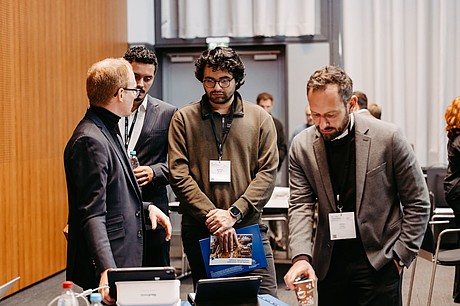 Drei Teilnehmer arbeiten gemeinsam an einem Gerät während eines praktischen Workshops.