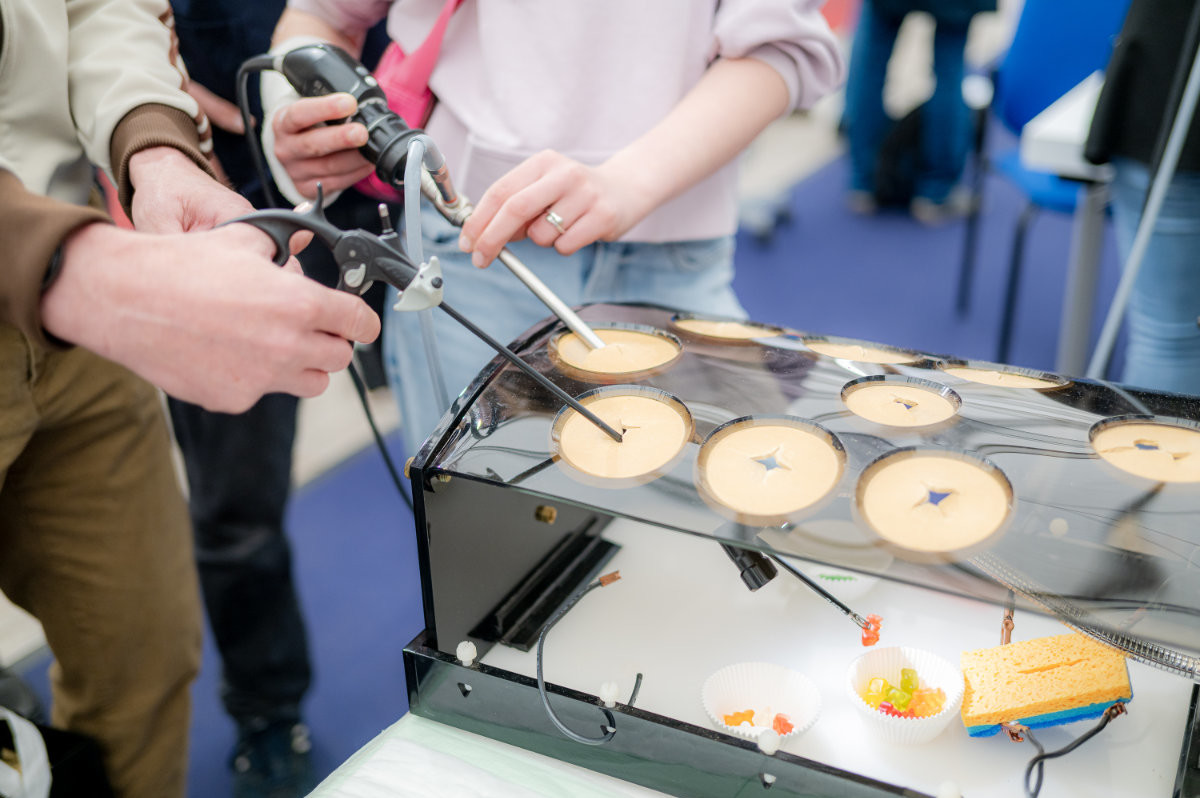 Zwei Personen bedienen chirurgische Instrumente an einem Trainingsmodell mit mehreren runden Öffnungen