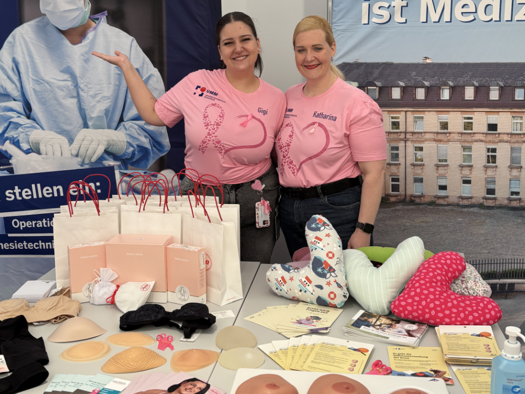 Zwei Frauen in pinken T-Shirts informieren zum Thema Brustkrebs.